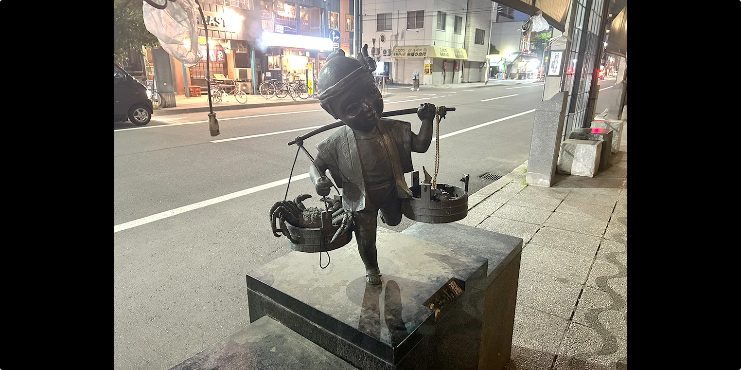 天秤棒を担いだ棒手振りのブロンズ像